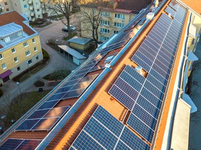 Aerial view of solar photo voltaic panels system on apartment building roof. Renewable ecological green energy production concept.